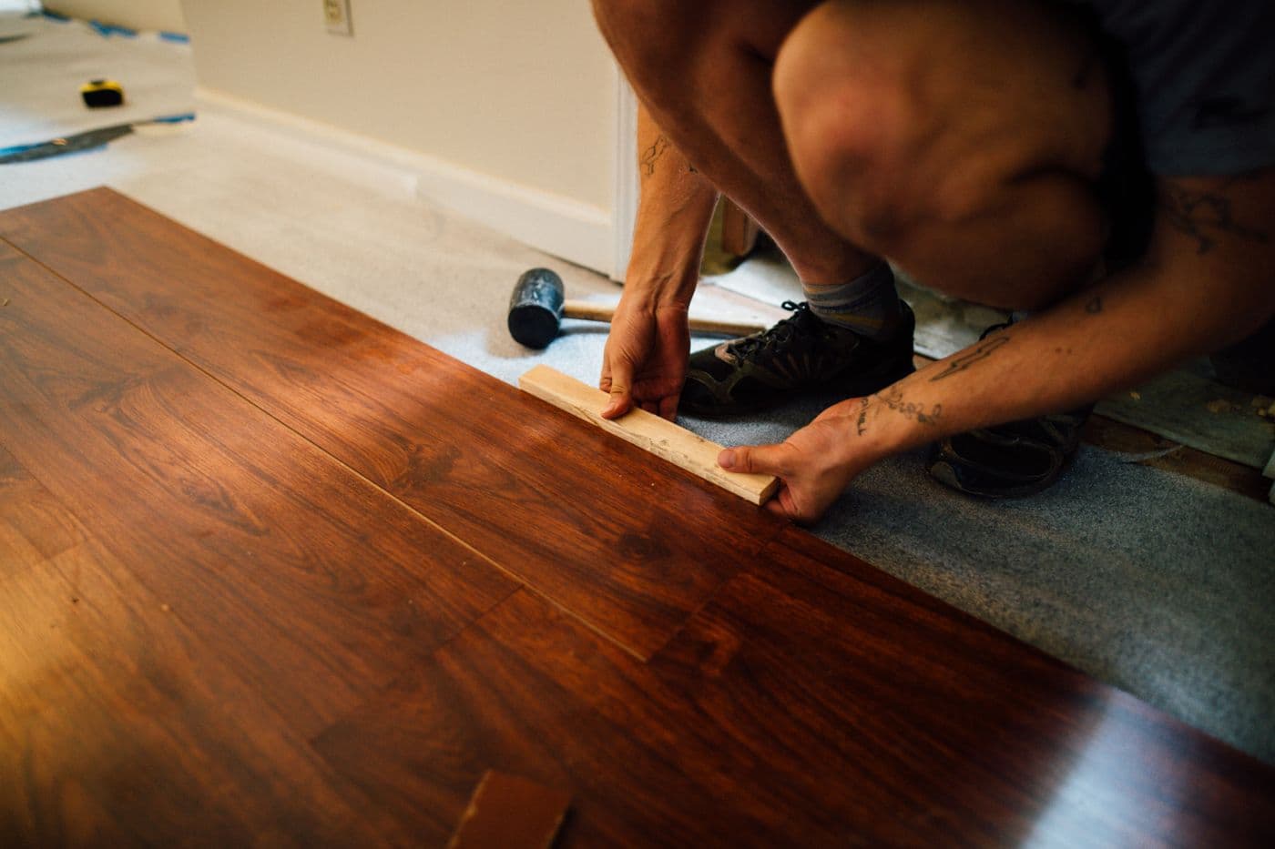 Flooring installer fitting hardwood planks during a home floor installation
